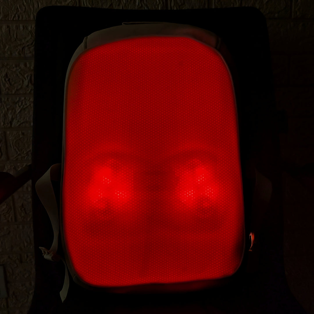 A red LED light therapy face mask glowing brightly, set against a dark background.